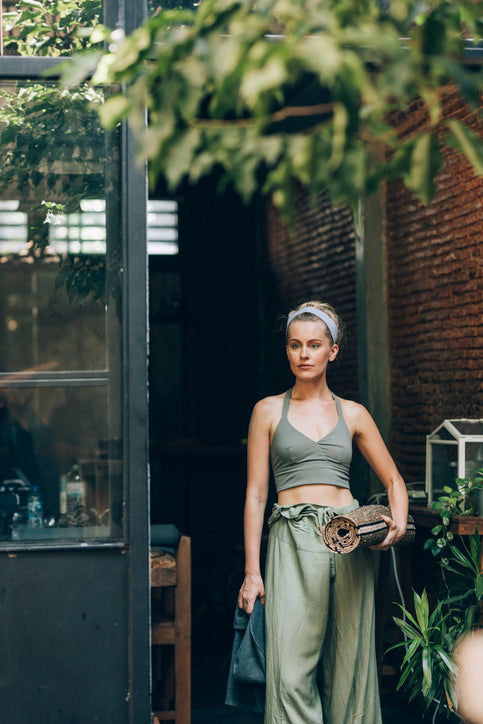 Vrouw met een opgerolde yogamat bij de ingang